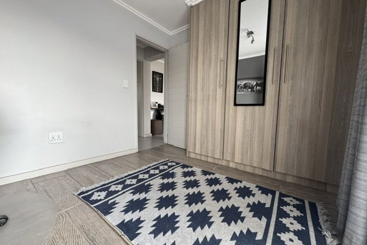 A well-maintained bedroom featuring modern wood-look built-in cupboards, tiled flooring, and classic cove cornice detailing.
