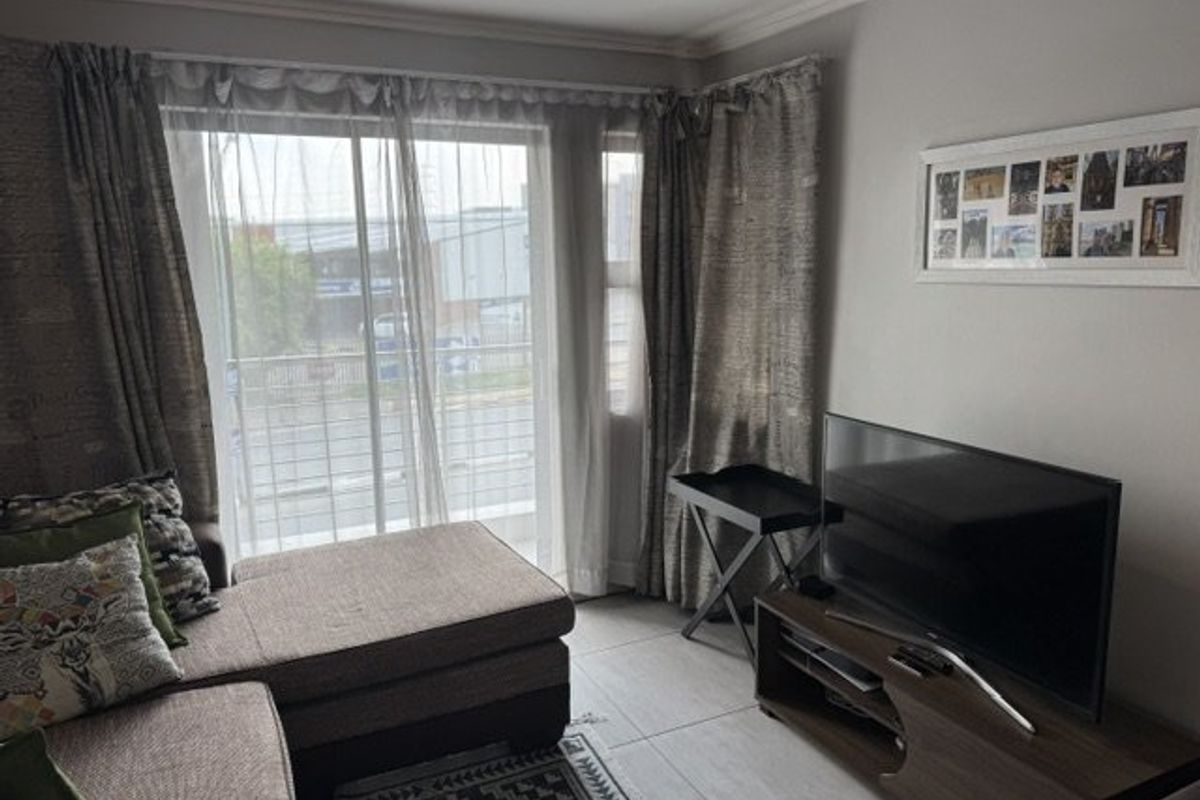 A living room featuring tiled flooring, neutral wall finishes, and a large sliding glass door providing natural light and access to the exterior.