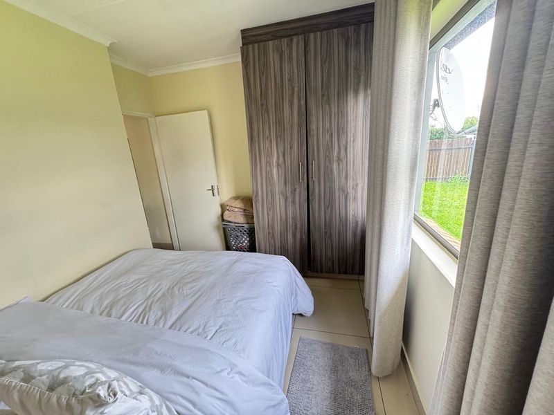 A functional bedroom featuring tiled flooring and a built-in wardrobe with wood-grain finish, providing practical storage space.