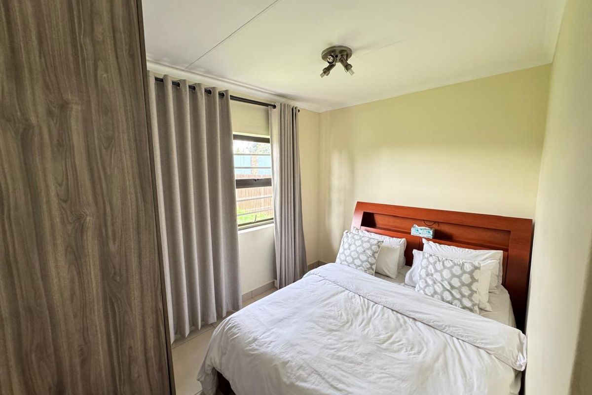 A well-maintained bedroom featuring tiled flooring, a built-in wardrobe, and a ceiling-mounted spotlight fixture, offering a clean and functional living space.