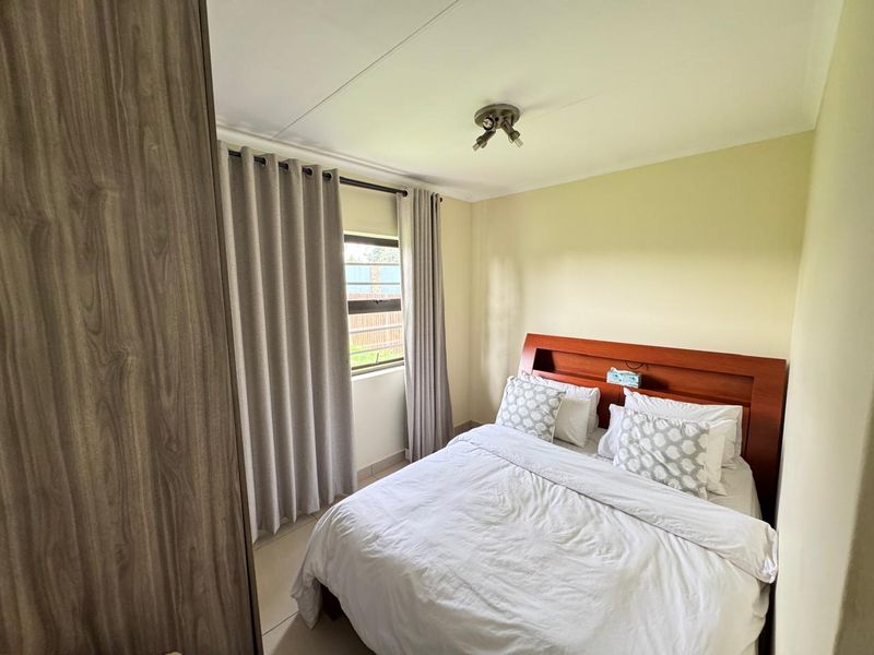 A well-maintained bedroom featuring tiled flooring, a built-in wardrobe, and a ceiling-mounted spotlight fixture, offering a clean and functional living space.