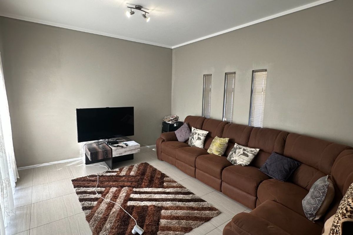 A well-maintained living room featuring neutral wall tones, large format floor tiles, and modern vertical slit windows, providing a clean and functional living space.