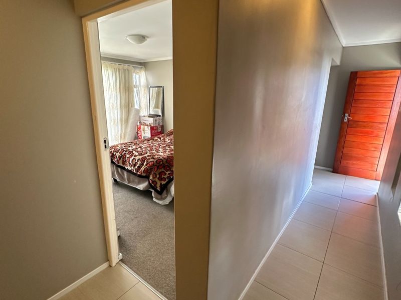 A tiled hallway providing access to a bedroom and featuring a solid wooden door.