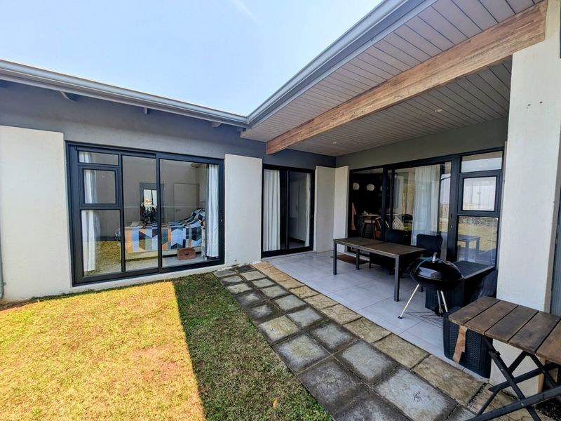 A covered patio area featuring tiled flooring, an exposed timber beam, and large sliding glass doors providing access to the interior living spaces.