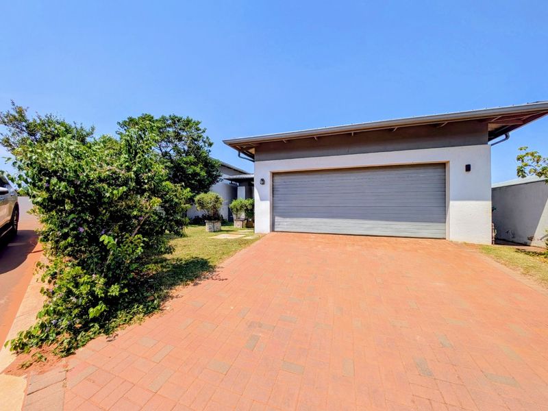 Front view of the property featuring a paved driveway leading to a single garage with a modern pitched roof design.