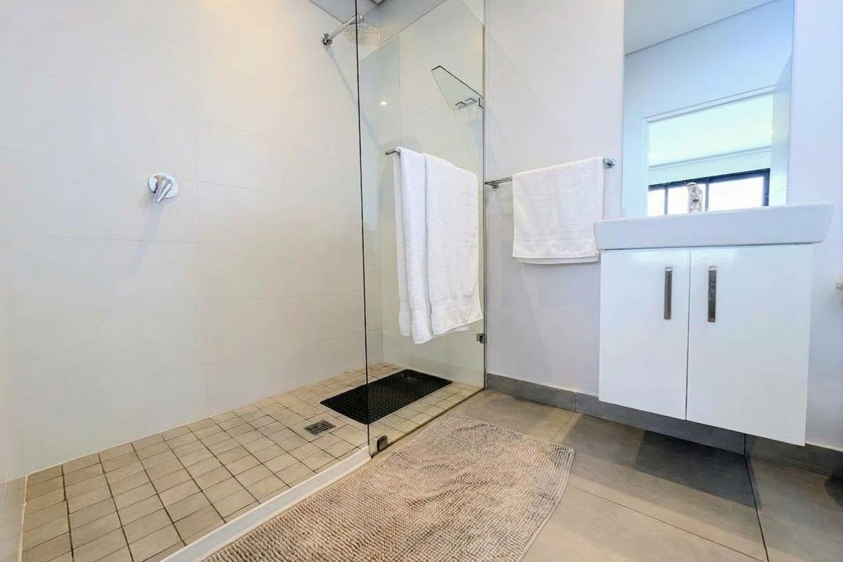 Modern bathroom featuring a spacious walk-in shower with glass screen and a sleek wall-mounted vanity unit.