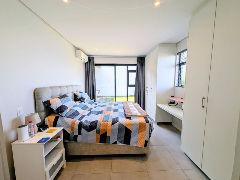 Modern bedroom featuring tiled floors, built-in cupboards, a built-in desk, split-system air conditioning, and direct access to the outdoor area via sliding glass doors.