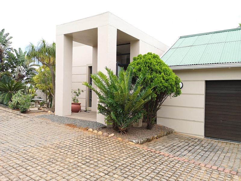 Modern front facade featuring a covered entrance portico, paved driveway, and a neat garden area with a single garage.