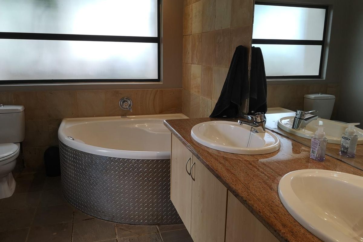 Bathroom featuring a corner bathtub, double vanity with granite countertops, and tiled finishes throughout.