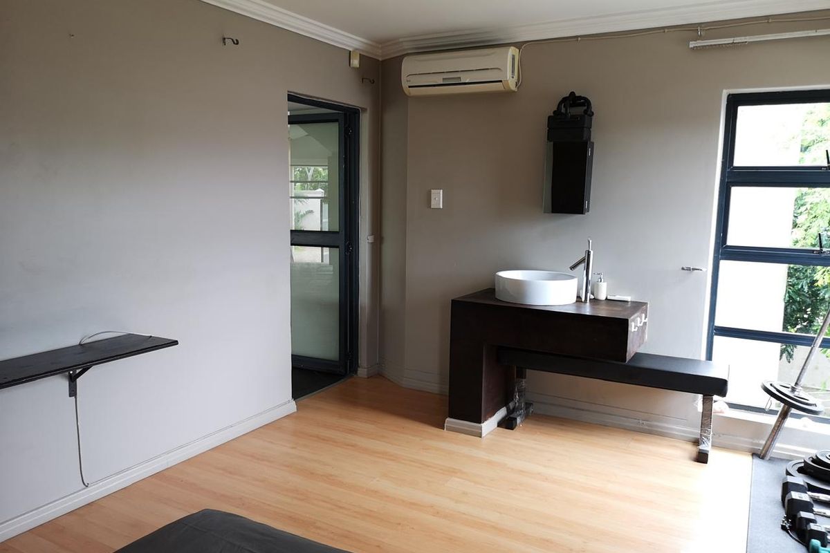 Bedroom featuring laminate flooring, an integrated vanity with a vessel sink, air conditioning, and aluminium window frames.