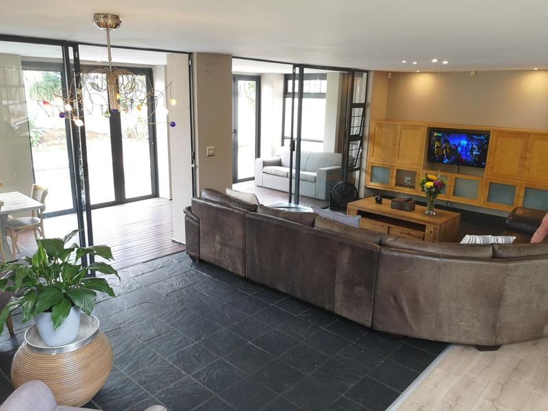 Spacious living area featuring slate flooring, built-in cabinetry, and large sliding glass doors that open onto an outdoor timber deck.