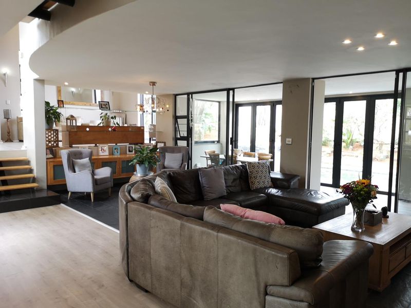 Spacious open-plan living area featuring a split-level design, slate and laminate flooring, and large sliding glass doors providing seamless access to the outdoor space.