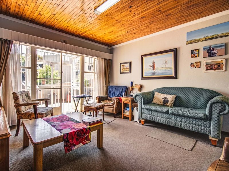 A living room featuring a timber tongue and groove ceiling, carpeted flooring, and a sliding glass door providing access to an outdoor area.