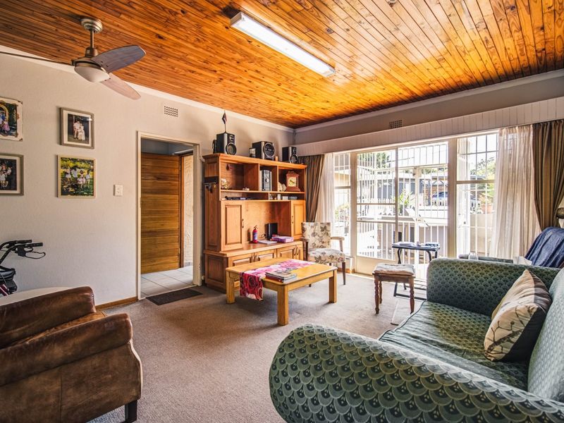 A living room featuring a timber tongue and groove ceiling, ceiling fan, and large sliding glass doors providing access to the exterior.