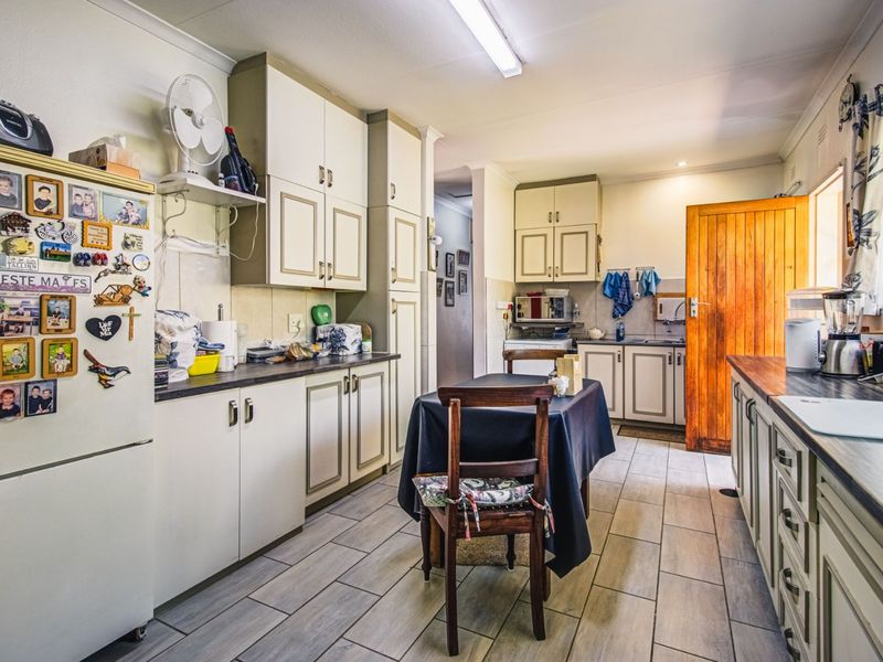 A functional kitchen featuring built-in cabinetry, laminate countertops, and tiled flooring, offering a practical layout with direct access to adjacent living areas.