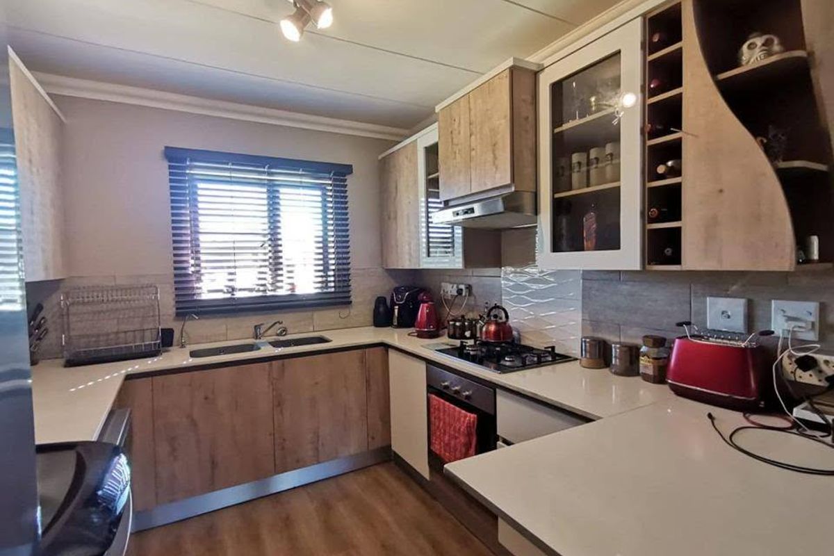 A well-appointed kitchen featuring wood-finish cabinetry, stone countertops, a gas hob with extractor, and integrated storage including a wine rack.