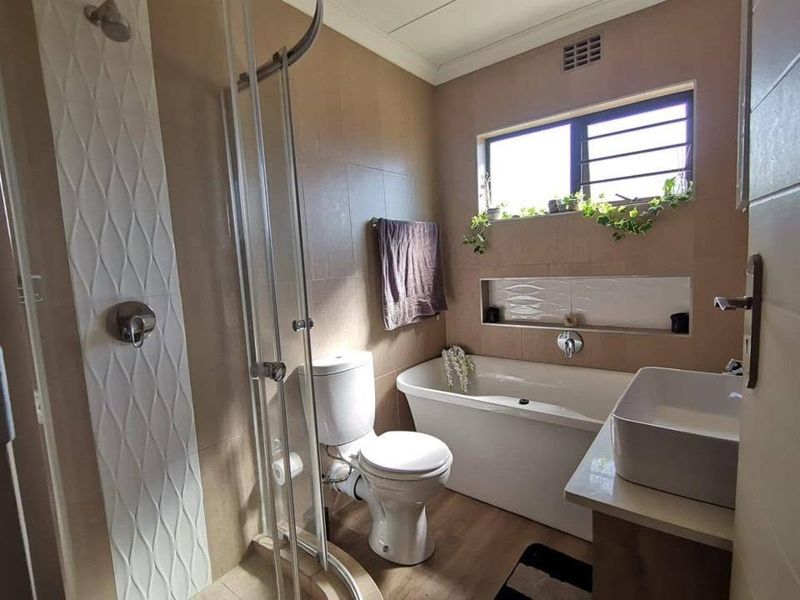 Modern bathroom featuring a freestanding bathtub, glass-enclosed shower, vessel sink, and built-in wall niche with neutral tiled finishes.