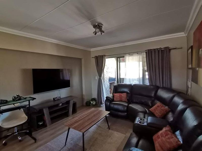 A comfortable living room featuring laminate flooring, coved ceilings, and a sliding glass door providing access to the outdoor area.