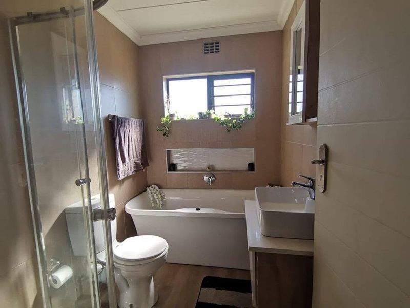 A modern bathroom featuring a freestanding bathtub, a glass-enclosed shower, a wall-mounted basin, and a convenient built-in wall niche for storage.
