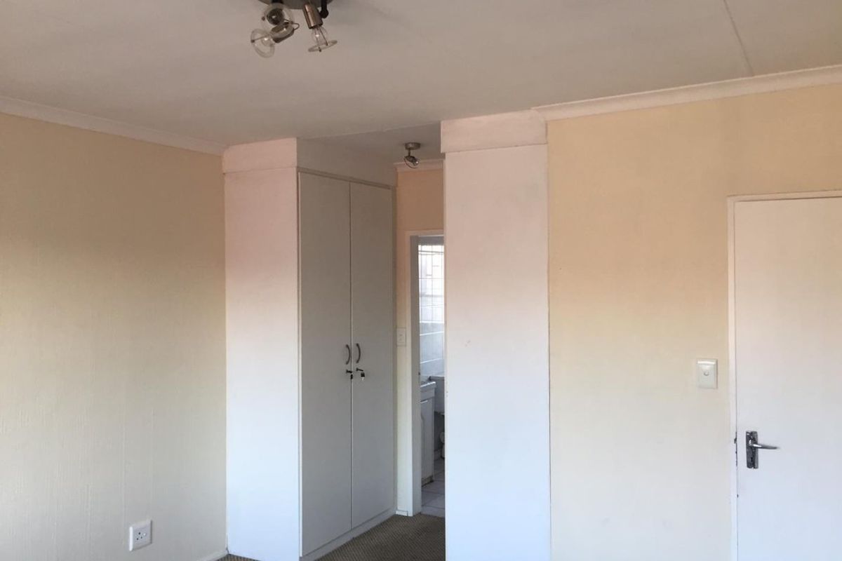 A vacant bedroom featuring built-in wardrobe storage, carpeted flooring, and ceiling-mounted lighting, offering a blank canvas for potential updates.