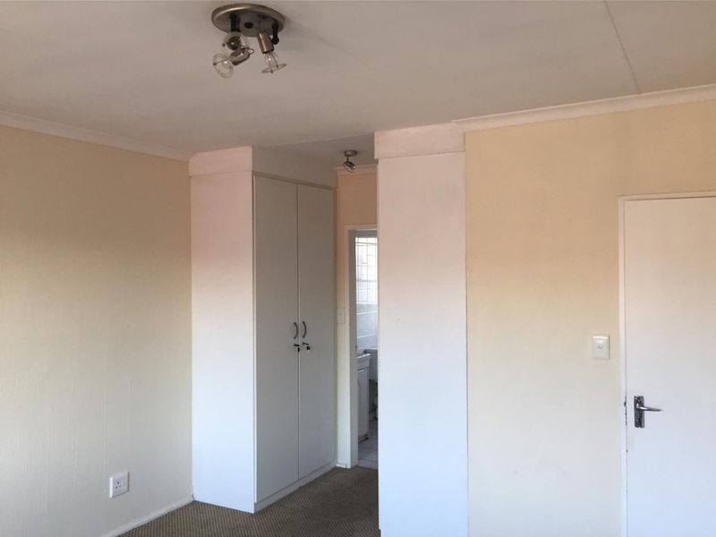 A vacant bedroom featuring built-in wardrobe storage, carpeted flooring, and ceiling-mounted lighting, offering a blank canvas for potential updates.