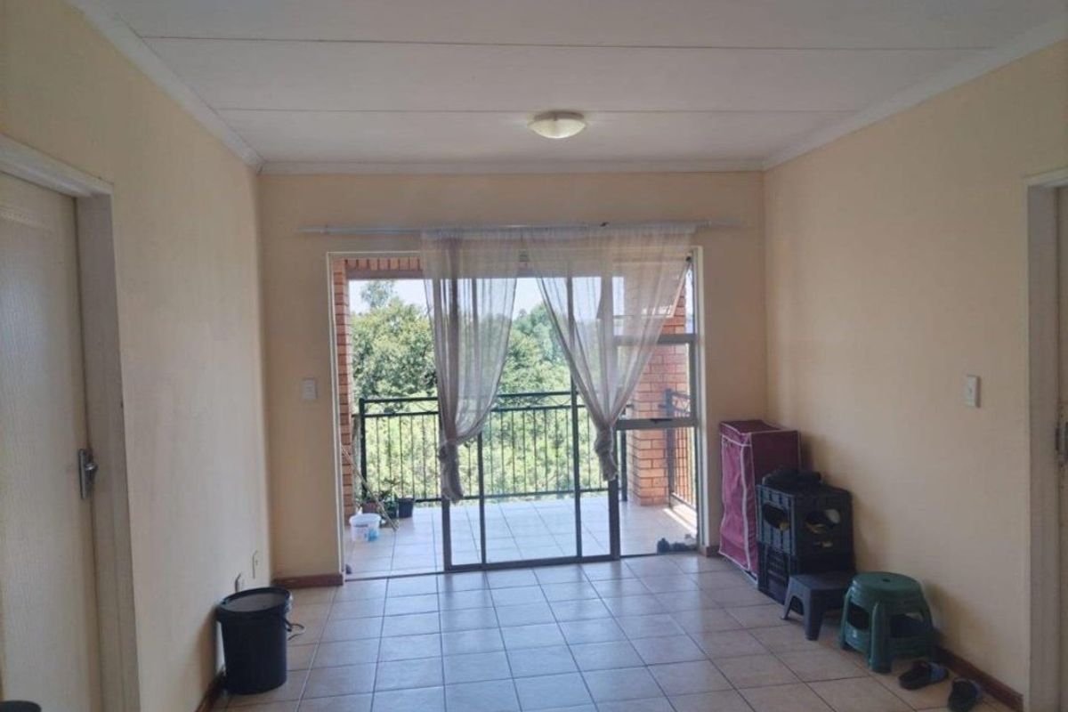 A simple living room featuring tiled flooring and a sliding glass door that provides direct access to an outdoor balcony.