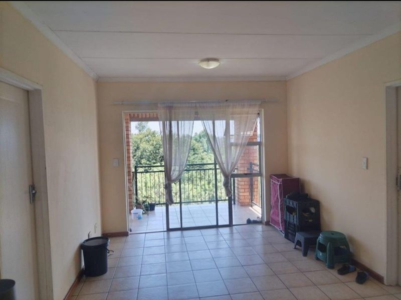 A simple living room featuring tiled flooring and a sliding glass door that provides direct access to an outdoor balcony.
