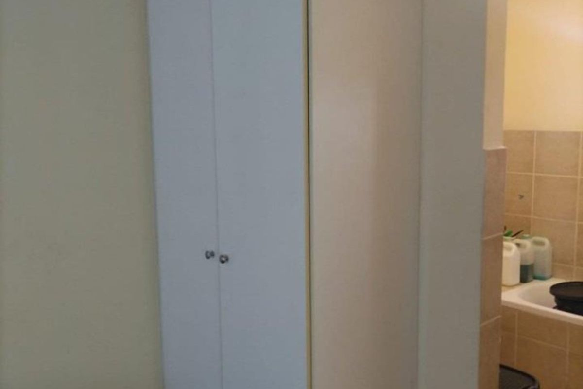 A bedroom featuring a built-in cupboard with white doors, adjacent to a tiled bathroom area.