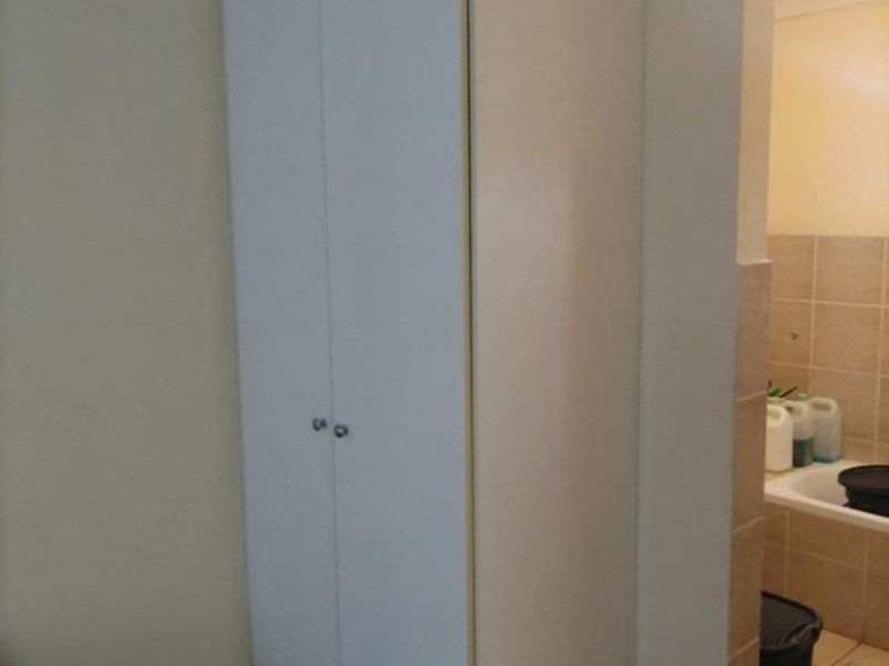 A bedroom featuring a built-in cupboard with white doors, adjacent to a tiled bathroom area.