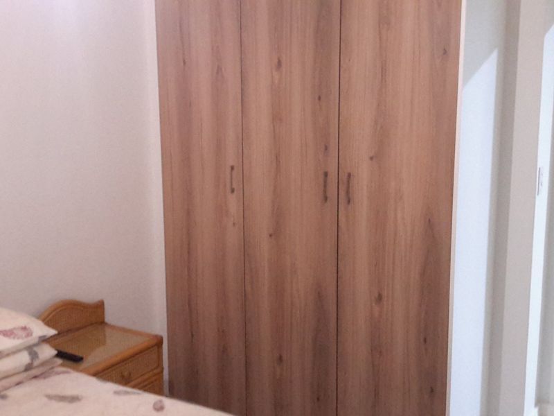 A bedroom featuring a wood-finish built-in wardrobe with ample storage space.