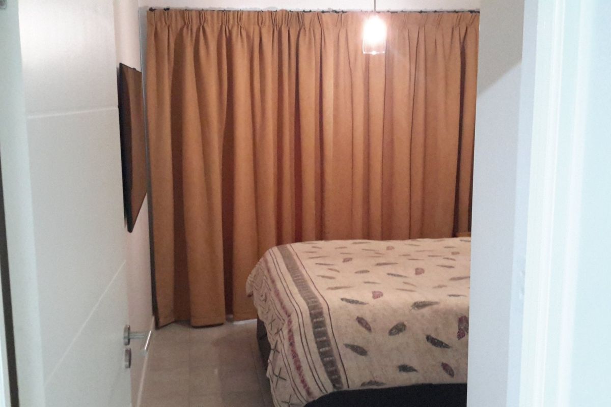 A bedroom featuring tiled flooring and a pendant light fixture, viewed from the doorway.