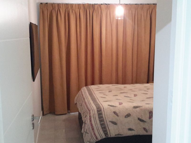A bedroom featuring tiled flooring and a pendant light fixture, viewed from the doorway.