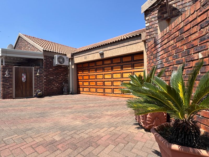 Front exterior view of a townhouse featuring a paved driveway, brick facade, and a wooden garage door.