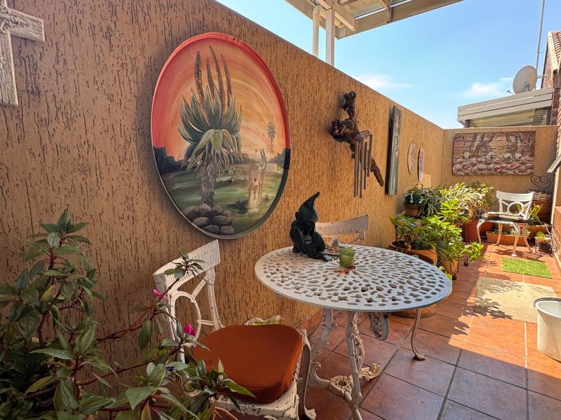 A covered outdoor patio area featuring tiled flooring and textured walls, providing a functional space for outdoor seating and relaxation.