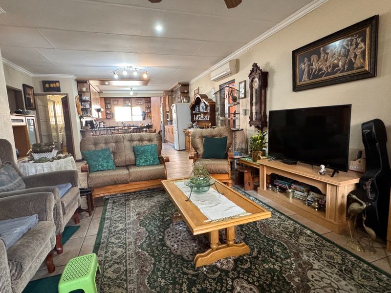 Spacious open-plan living area featuring tiled flooring, a ceiling fan, and an integrated kitchen with cabinetry, creating a functional and connected living space.