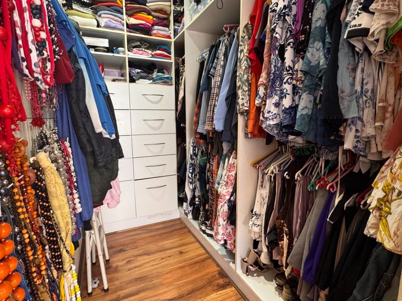 A walk-in closet featuring extensive built-in cabinetry, drawers, and hanging storage space with durable laminate flooring.