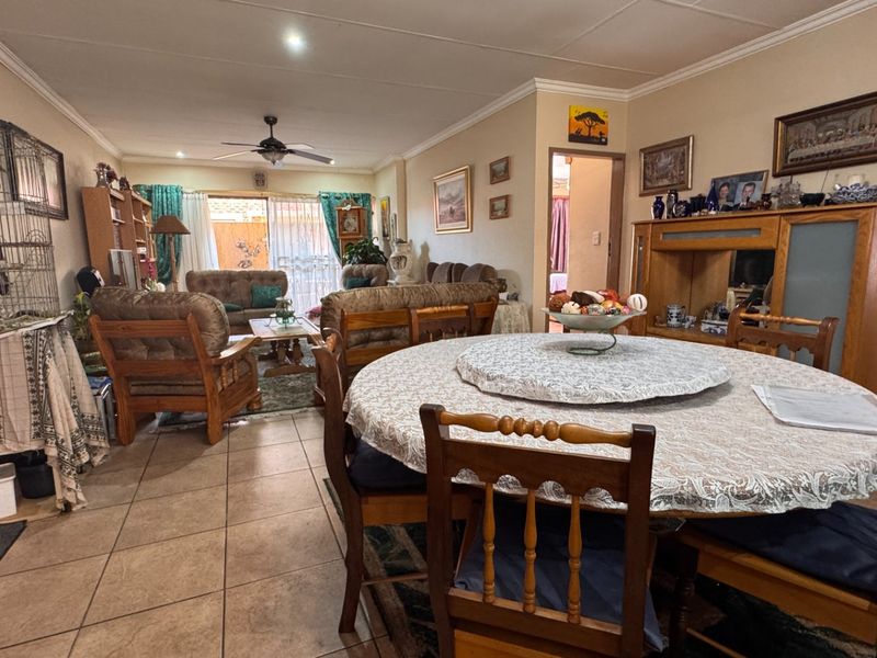 Spacious open-plan living and dining area featuring tiled flooring, a ceiling fan, and sliding glass doors leading to the outdoor space.