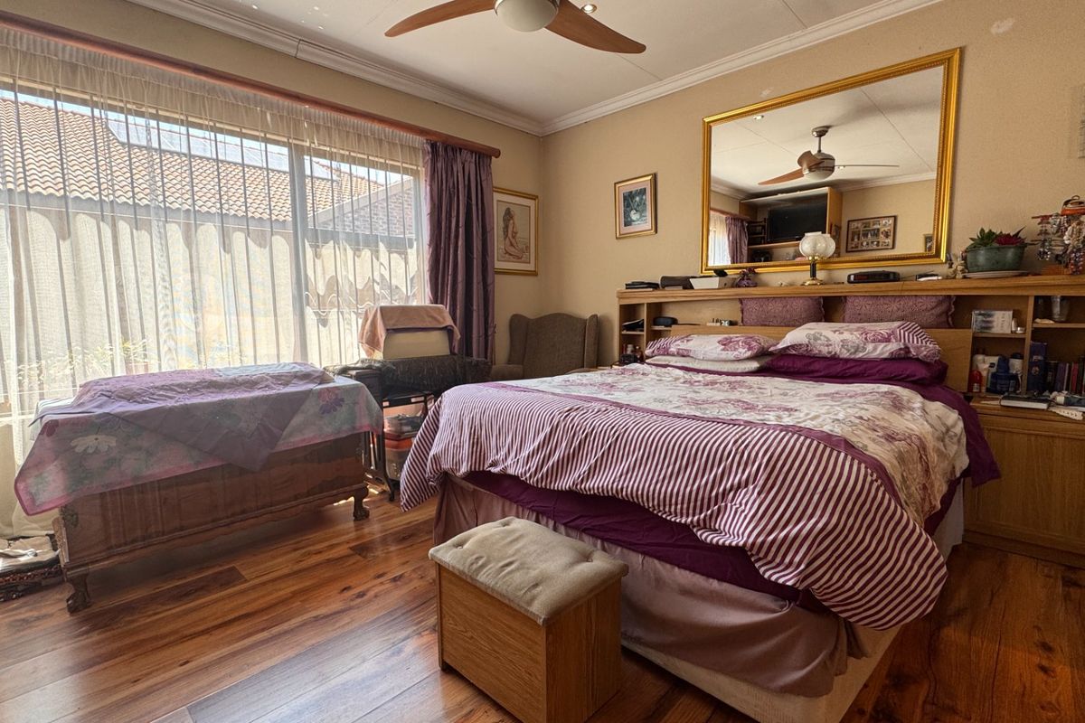 Spacious bedroom featuring warm hardwood flooring, a ceiling fan, and a large sliding glass door that provides ample natural light.