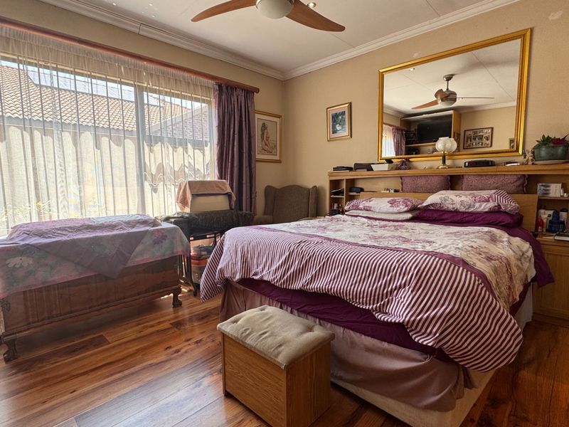 Spacious bedroom featuring warm hardwood flooring, a ceiling fan, and a large sliding glass door that provides ample natural light.