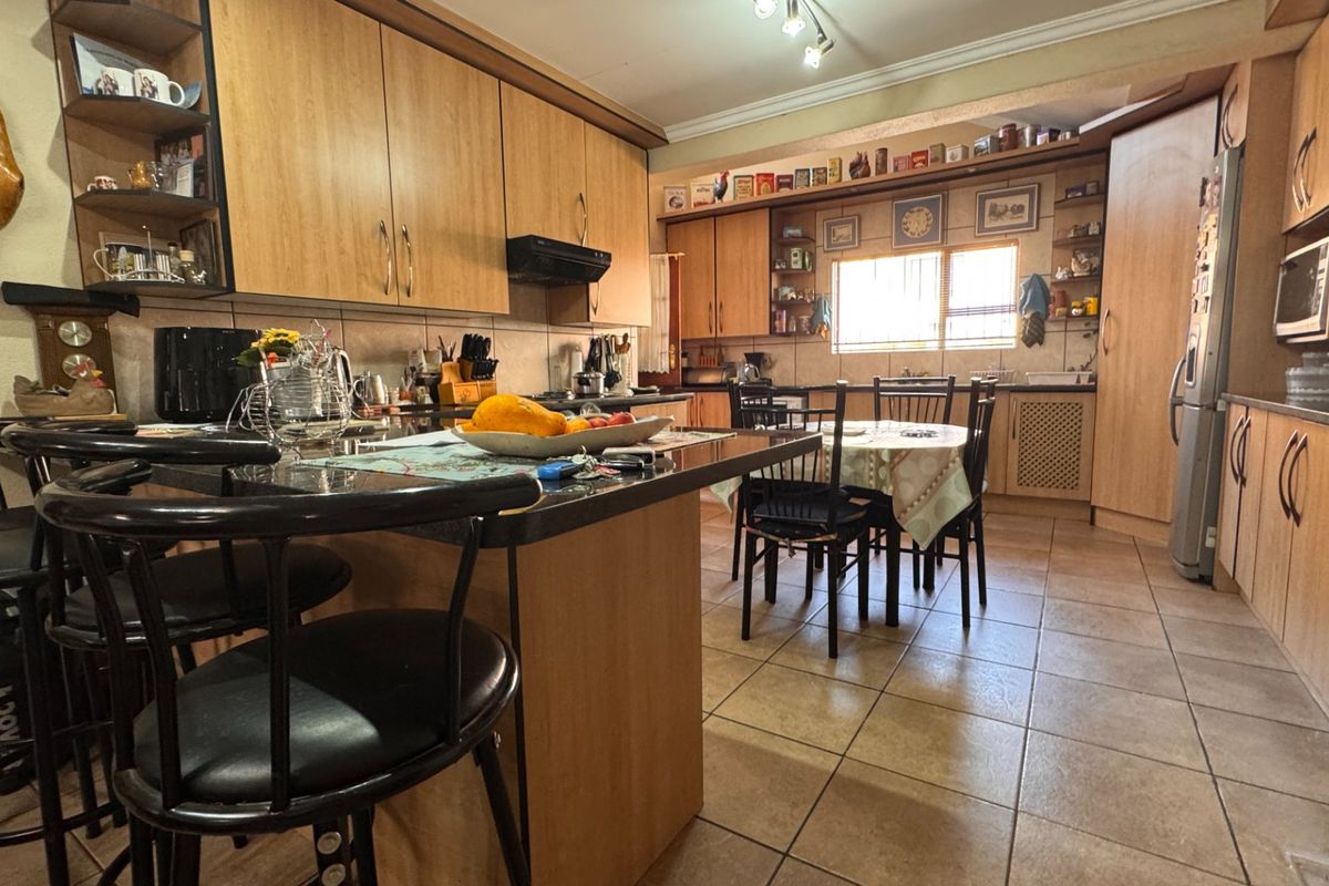 Spacious kitchen featuring laminate cabinetry, granite countertops, tiled flooring, and a central breakfast bar, offering a functional layout with ample storage space.