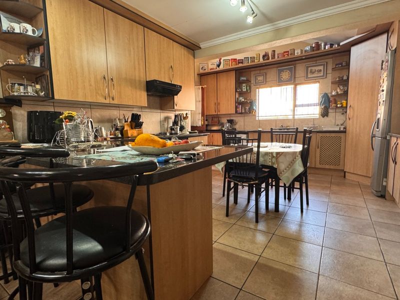 Spacious kitchen featuring laminate cabinetry, granite countertops, tiled flooring, and a central breakfast bar, offering a functional layout with ample storage space.
