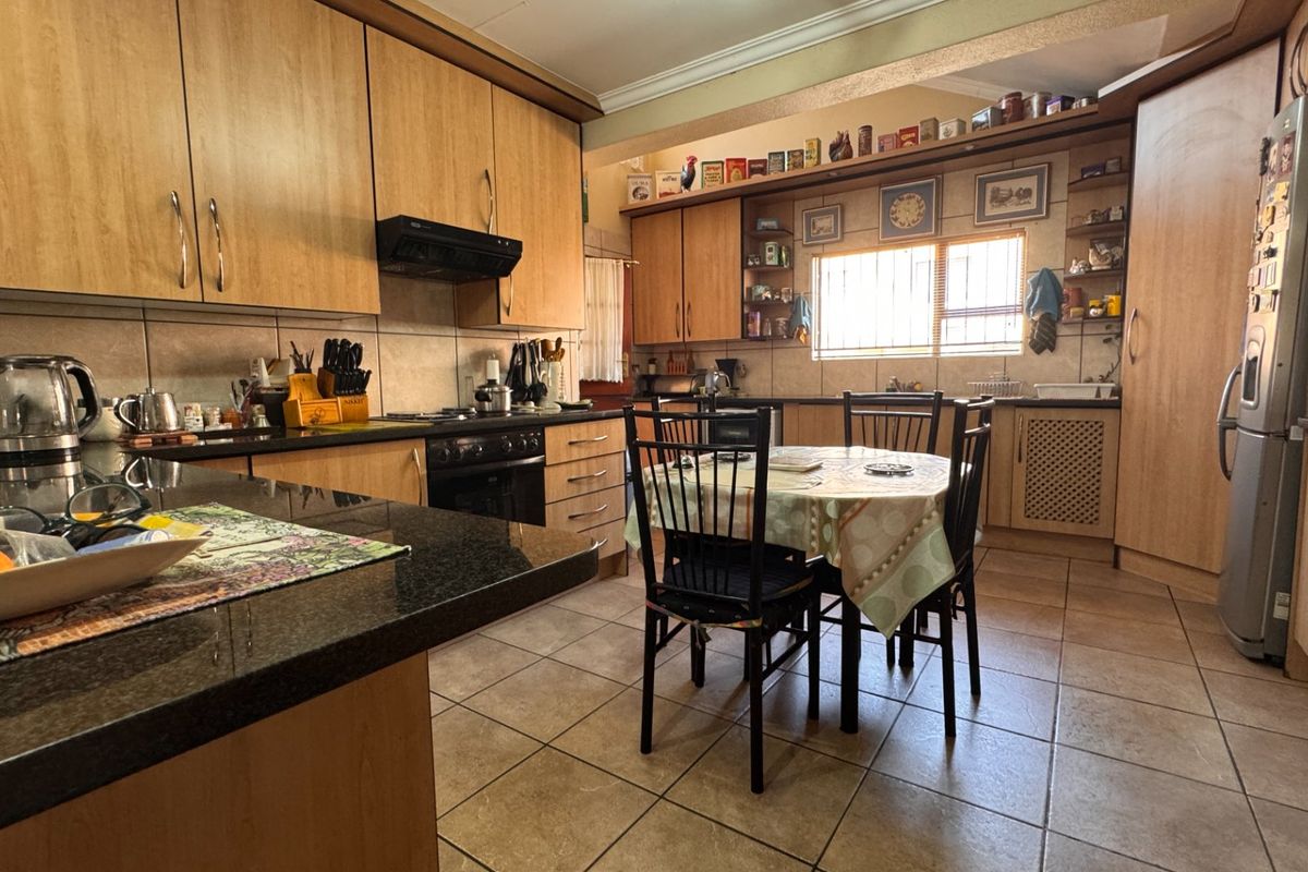 Open-plan kitchen and dining area featuring laminate cabinetry, granite countertops, built-in oven, extractor fan, and tiled flooring.