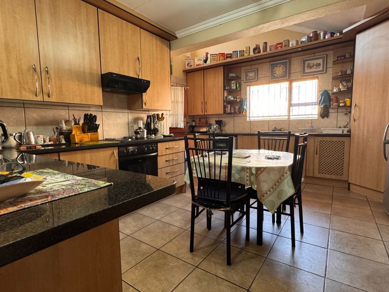 Open-plan kitchen and dining area featuring laminate cabinetry, granite countertops, built-in oven, extractor fan, and tiled flooring.