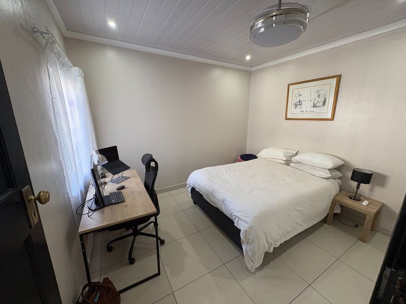 A well-maintained bedroom featuring tiled flooring, a tongue and groove ceiling with a central fan, and recessed lighting.