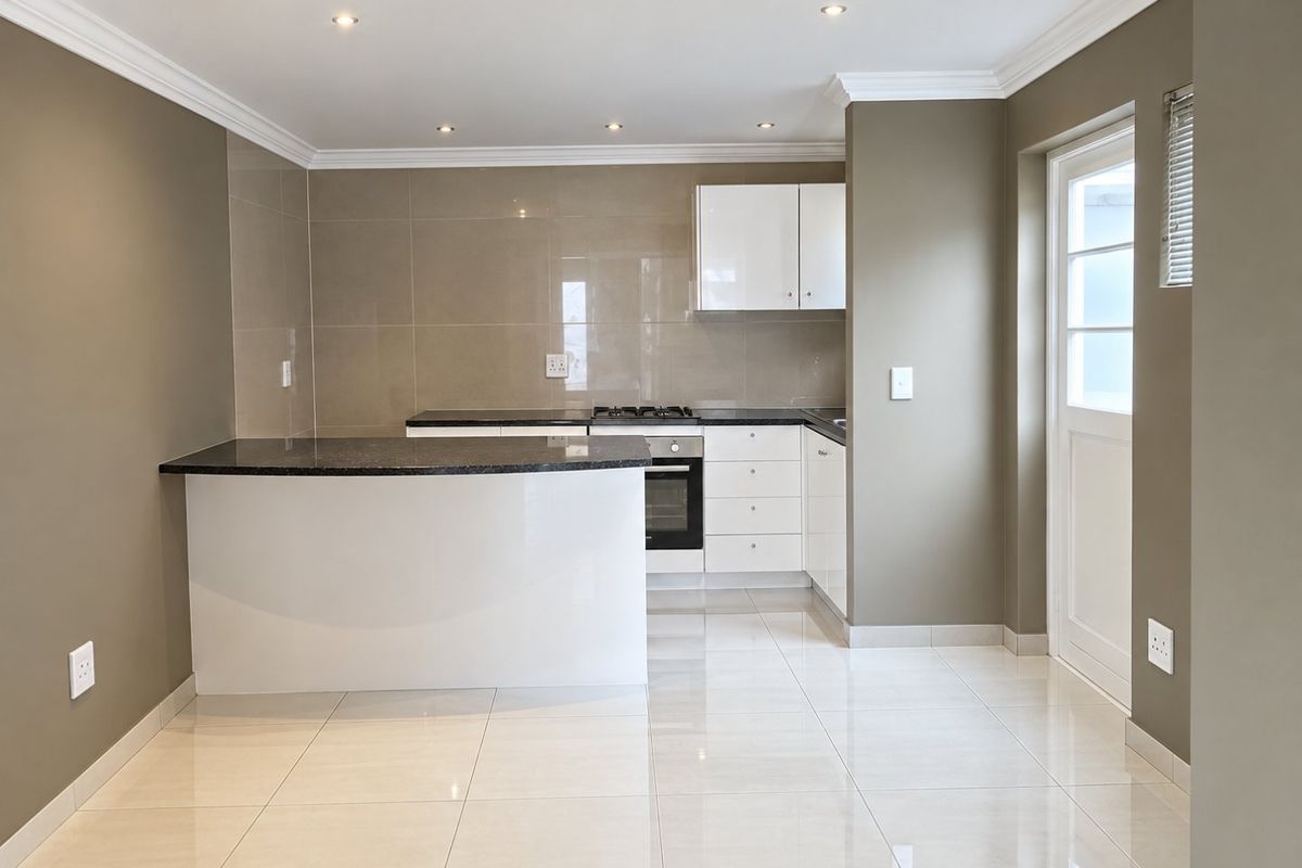 A clean, modern kitchen featuring white cabinetry, dark granite countertops, gas hob, built-in oven, and polished tiled flooring with direct exterior access.