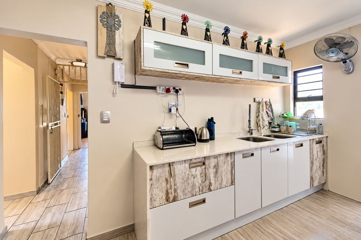 A functional kitchen featuring quartz countertops, double basin sink, and a mix of modern and rustic-style cabinetry with tiled flooring throughout.
