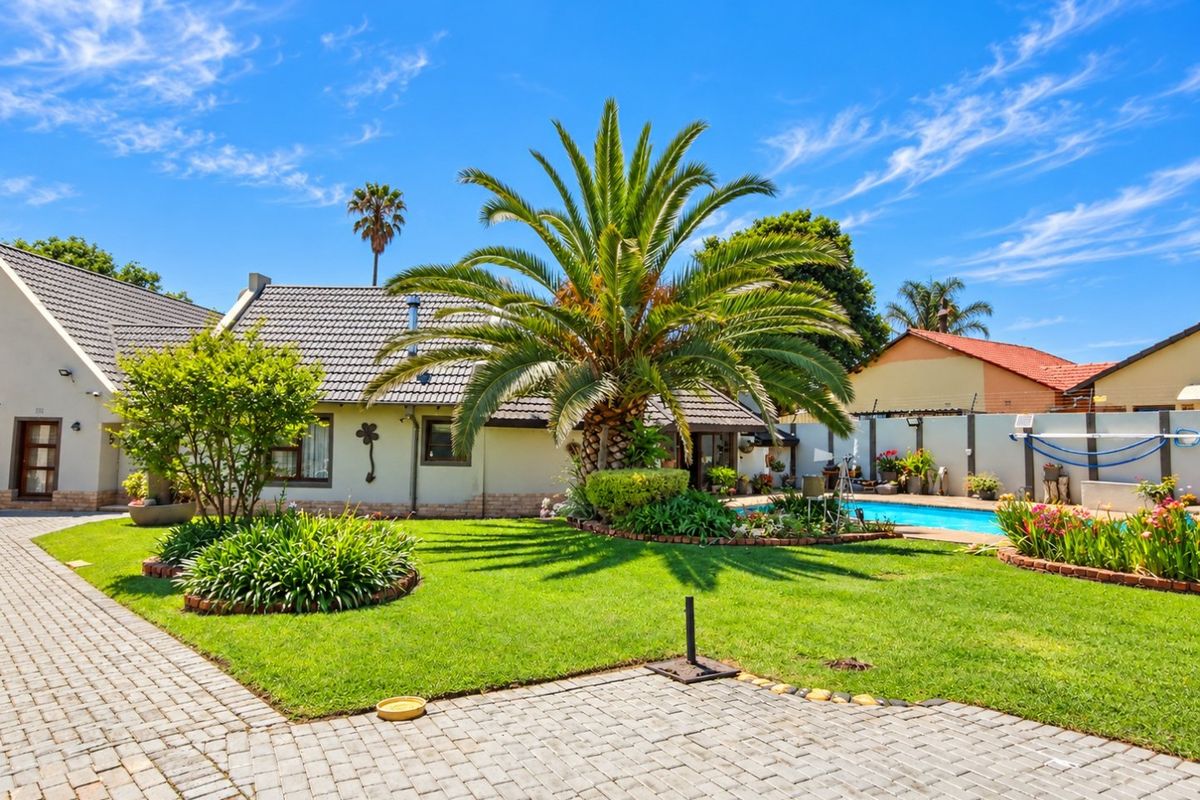 A well-maintained rear garden featuring a swimming pool, paved driveway, and established landscaping, providing a private outdoor entertainment area.
