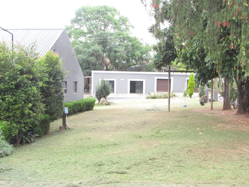 Spacious garden area featuring a view of the main dwelling and a separate garage structure with sliding doors and metal roofing.