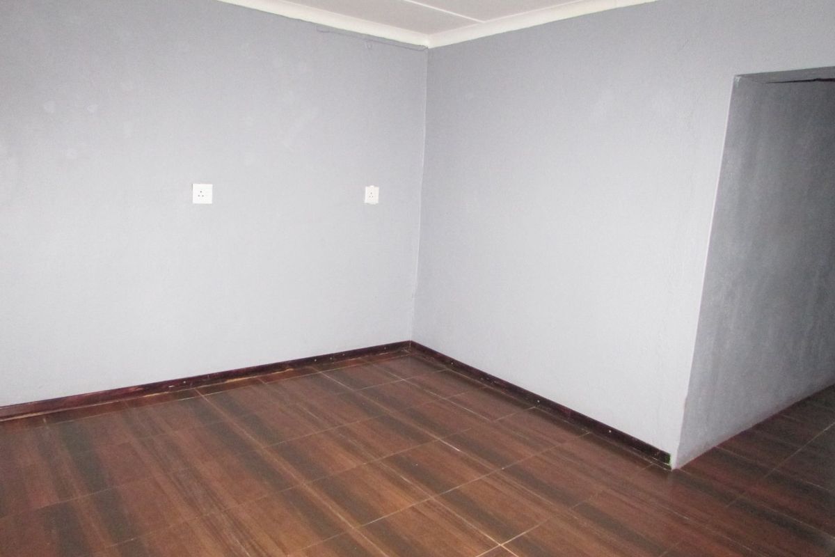 An empty bedroom featuring dark wood-look tiled flooring, grey painted walls, and coved ceiling details, ready for personalization.