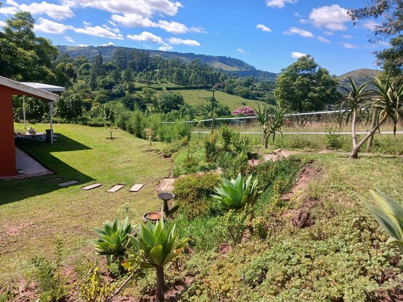A well-maintained garden area featuring a stone pathway, lush lawn, and scenic mountain views in the background.
